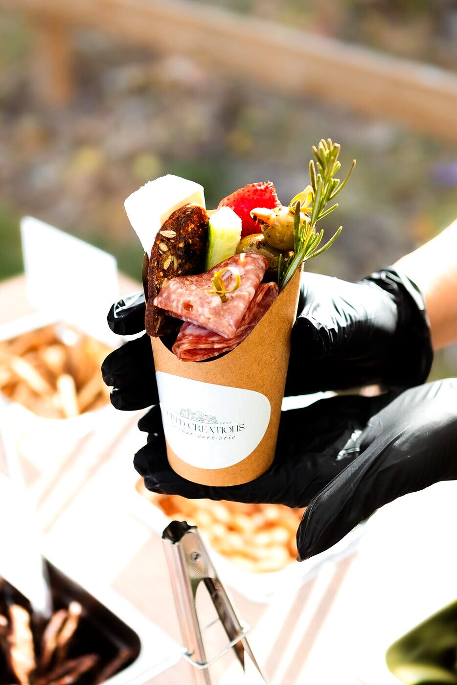 Individual Cured Creations charcuterie cup with a custom branded sticker, served at a corporate event