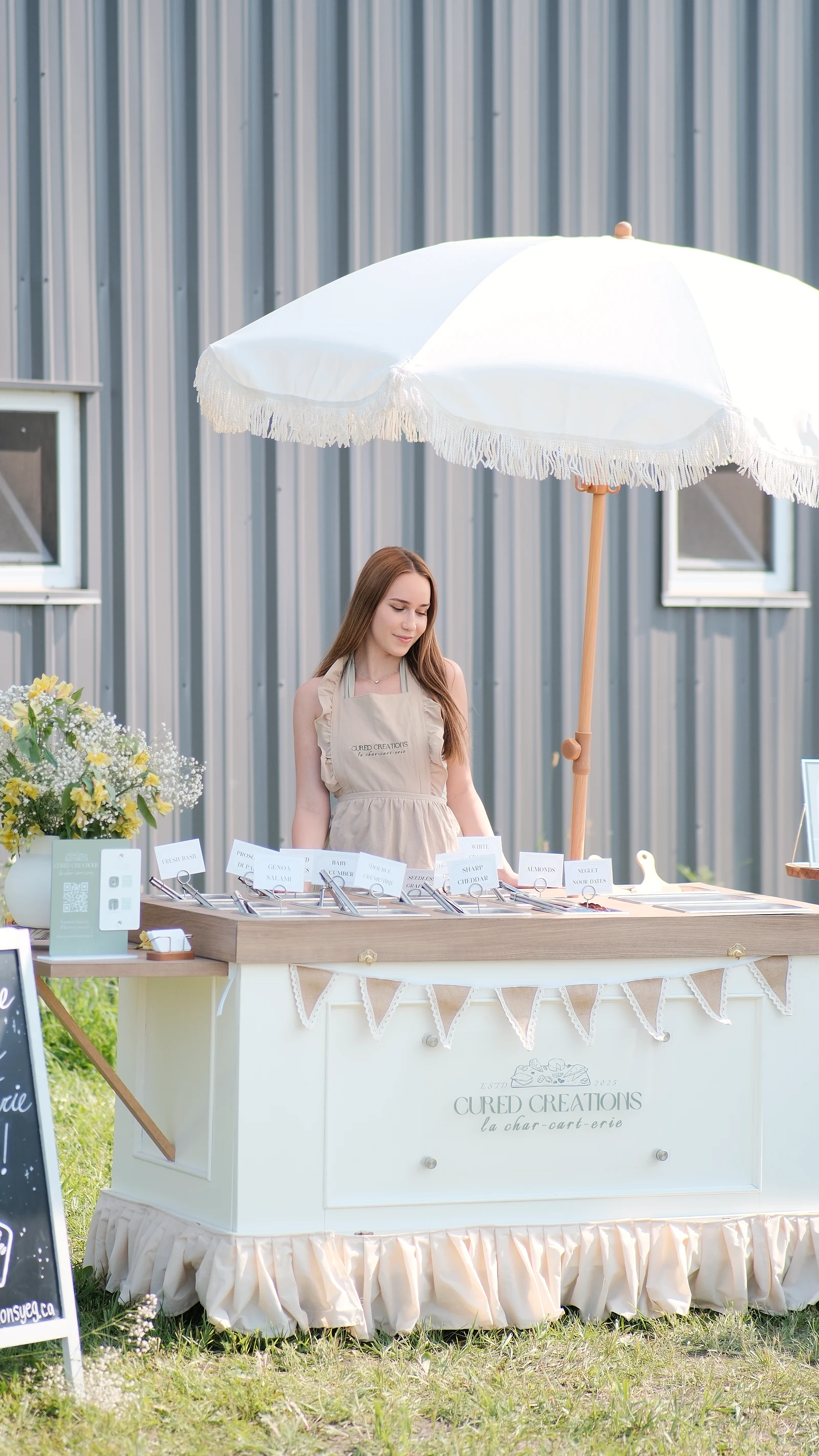 Sarah behind the white charcuterie cart and fringed parasol